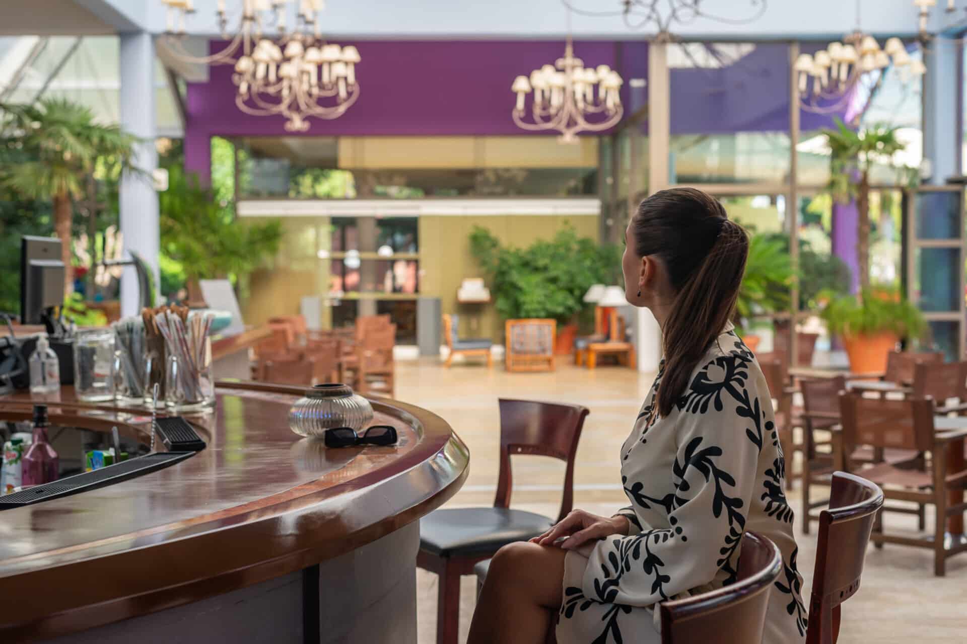 Woman seated at the lobby bar, enjoying a relaxed and stylish atmosphere