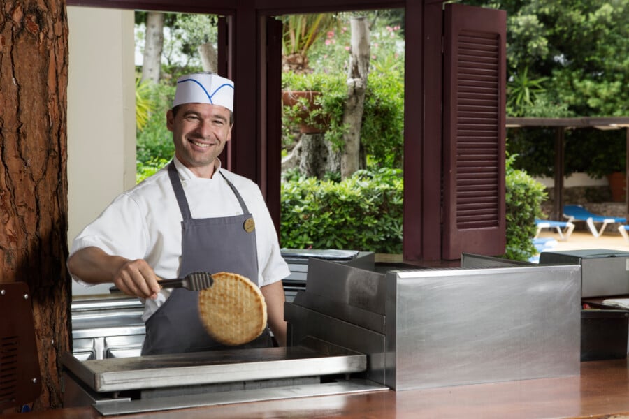 Chef preparing traditional Greek souvlaki, expertly holding a freshly made pita